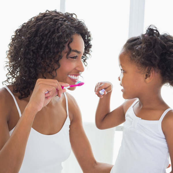 Mother and daughter brushing their teeth after a veneers procedure in Brookfield, WI