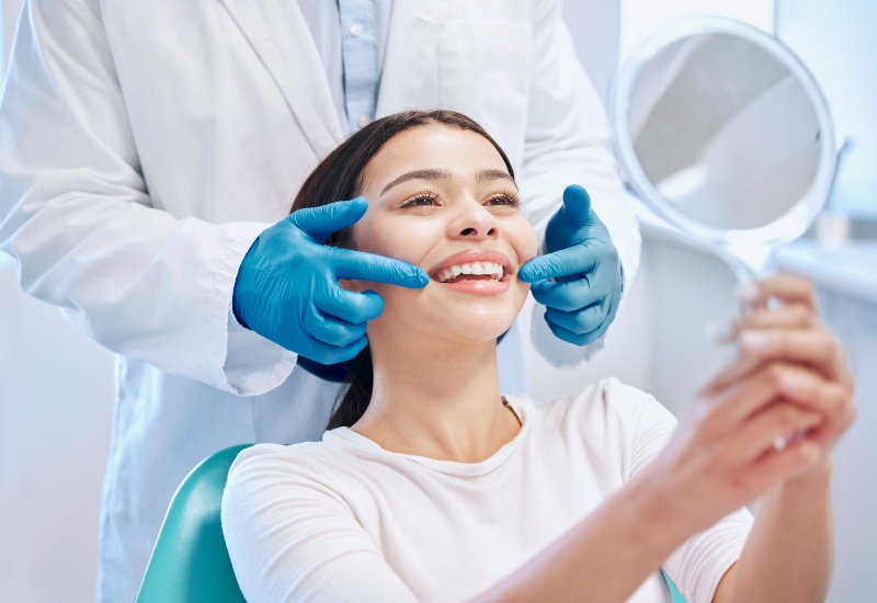 A happy woman examines her teeth with a dentist after a cosmetic dental treatment in Brookfield, WI
