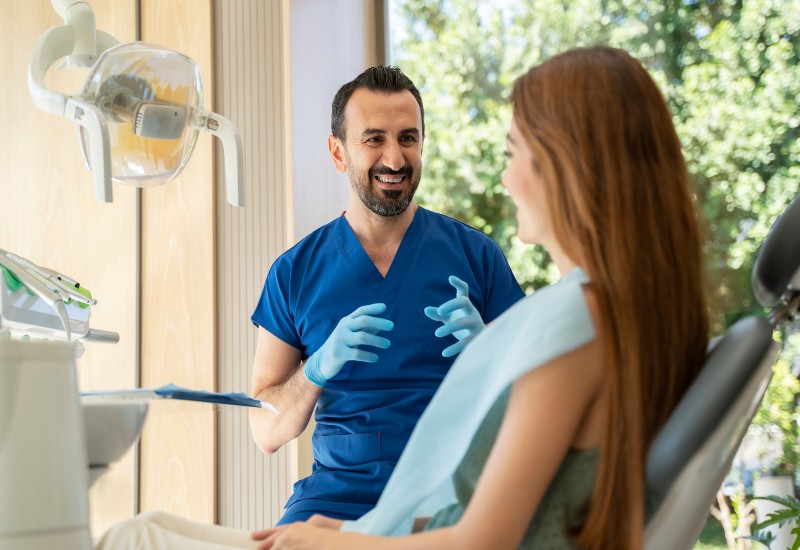 A dentist explaining to a patient how a dental bridge prevents shifting teeth in Brookfield, WI