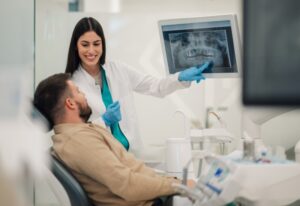 A dentist reviews an X‑ray with a patient, showing signs that require tooth extraction in Brookfield