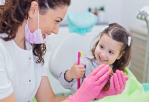 A dentist teaches brushing to a young girl, showcasing Preventive Dental Care in Brookfield, WI