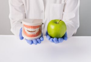 A dentist holds a dental model & an apple, promoting nutrition for healthy smiles in Brookfield, WI