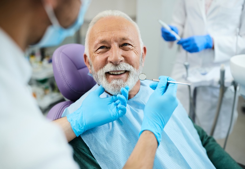 A dentist discussing oral health & heart disease with an elderly man during a check-up in Brookfield